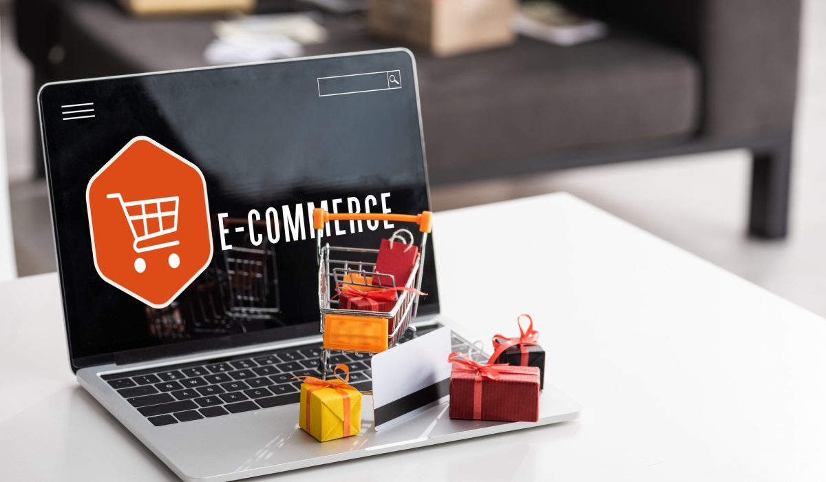 Toy gift boxes and credit card on laptop with e-commerce lettering on table